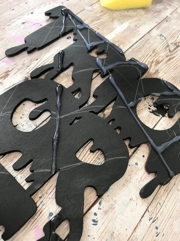 Adding hot glue to the spider's web on a trick or treat sign 